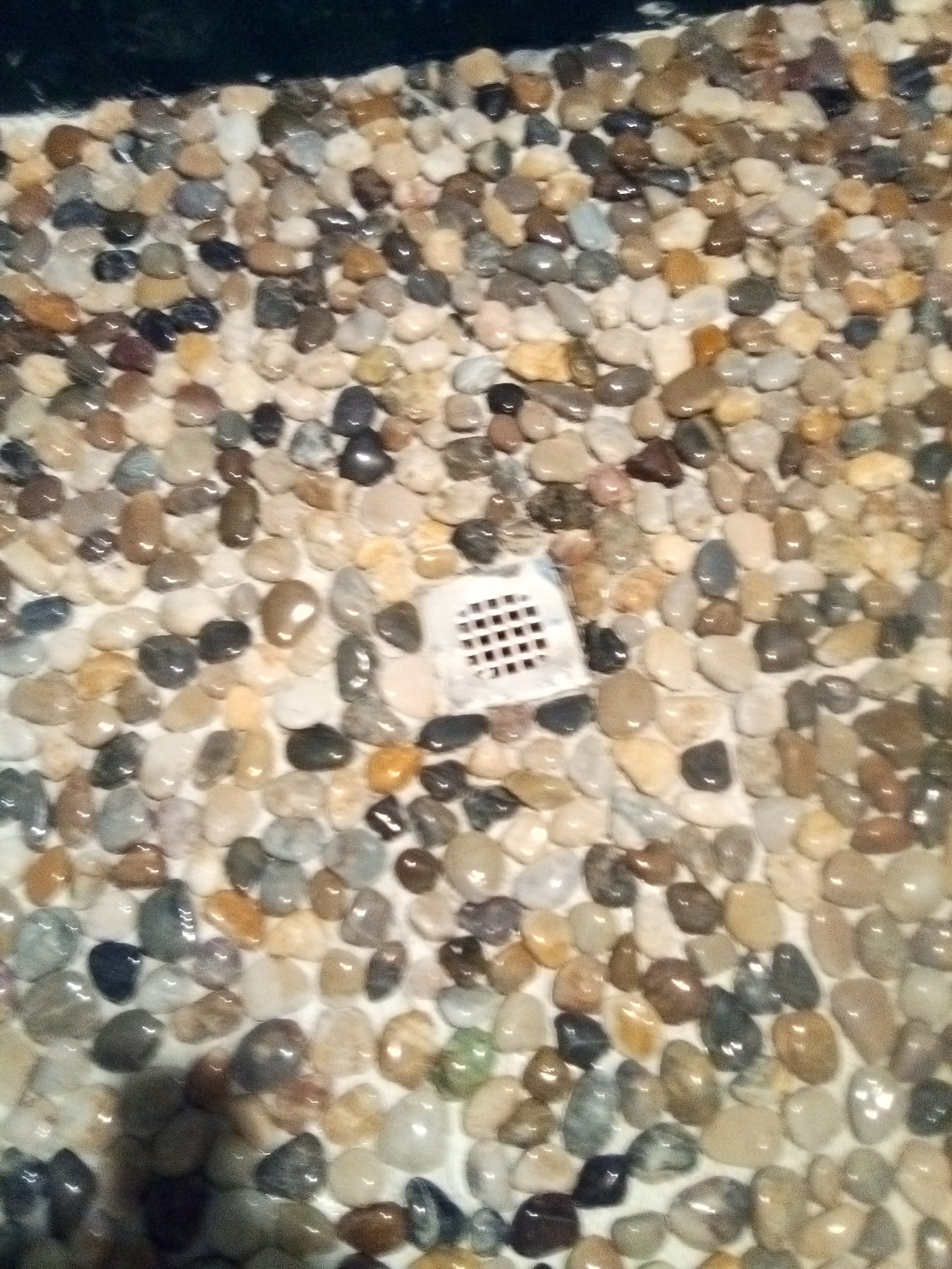 The pebble floor falling to a linear drain.