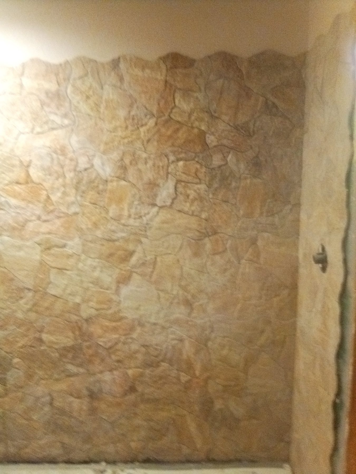 Textured stone wall panel installed floor to ceiling.
