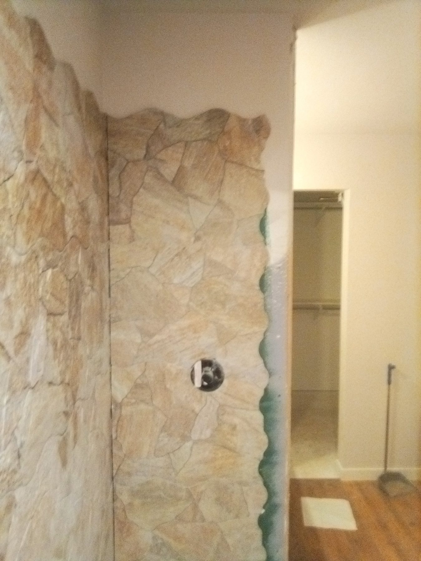 The stone wall running past the doorway into the hall.