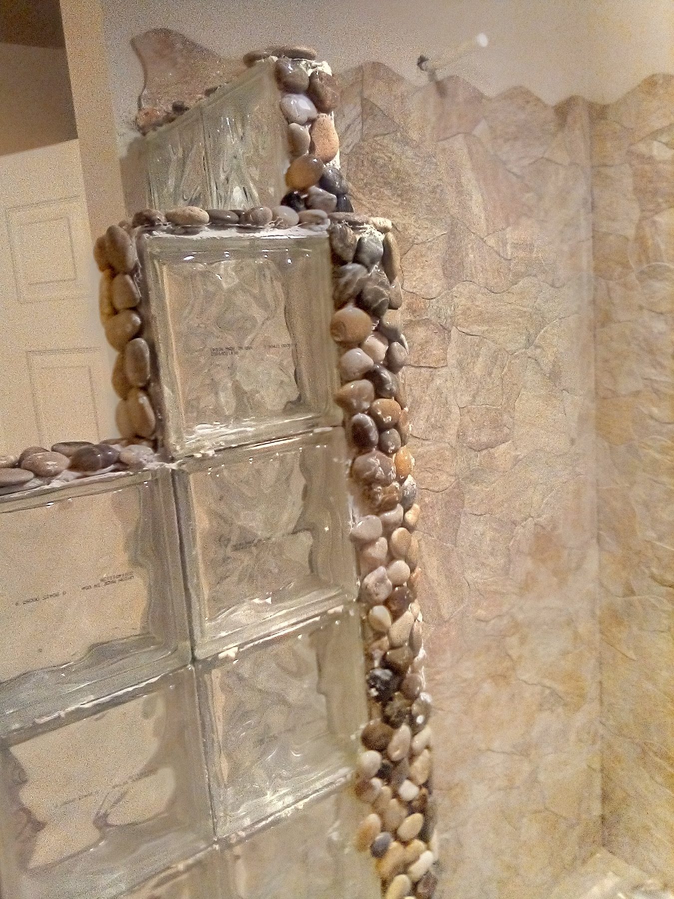 Glass block and river-rock trim column beside the shower entry.