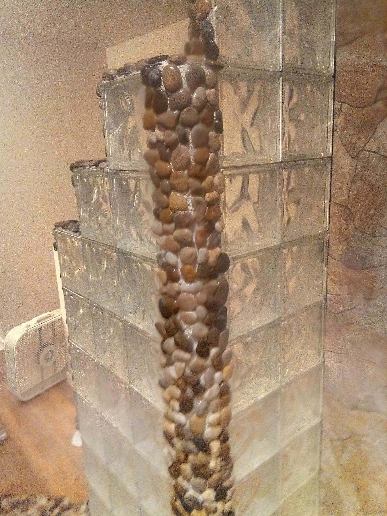 The completed shower: glass block wall, stone panel, river-rock column.