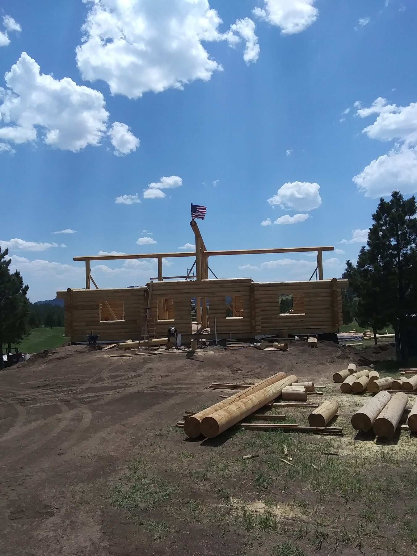 The first courses of log wall standing, with a crane boom over the site.