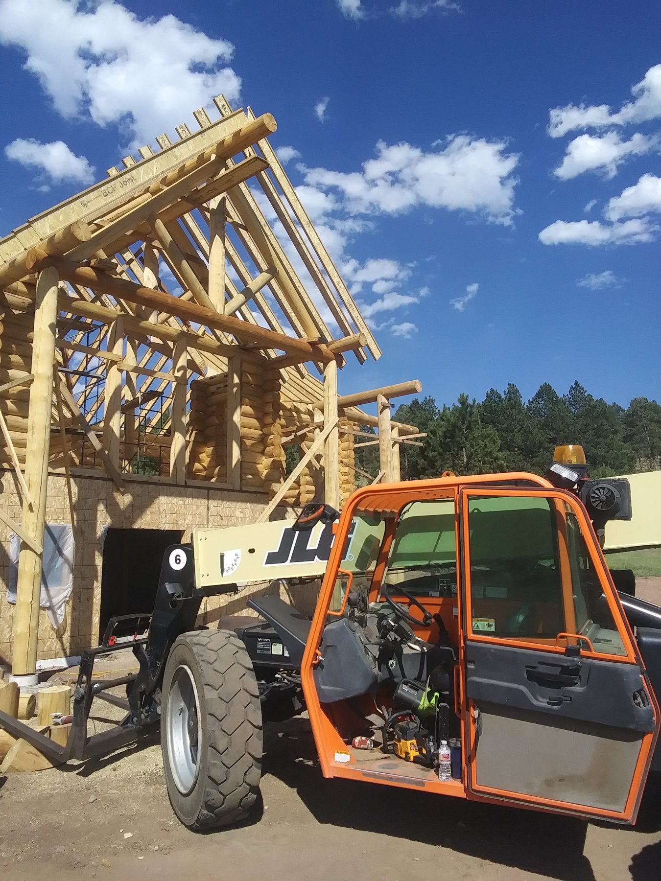 A gable truss set into place, scaffolding and ladders still against the wall.