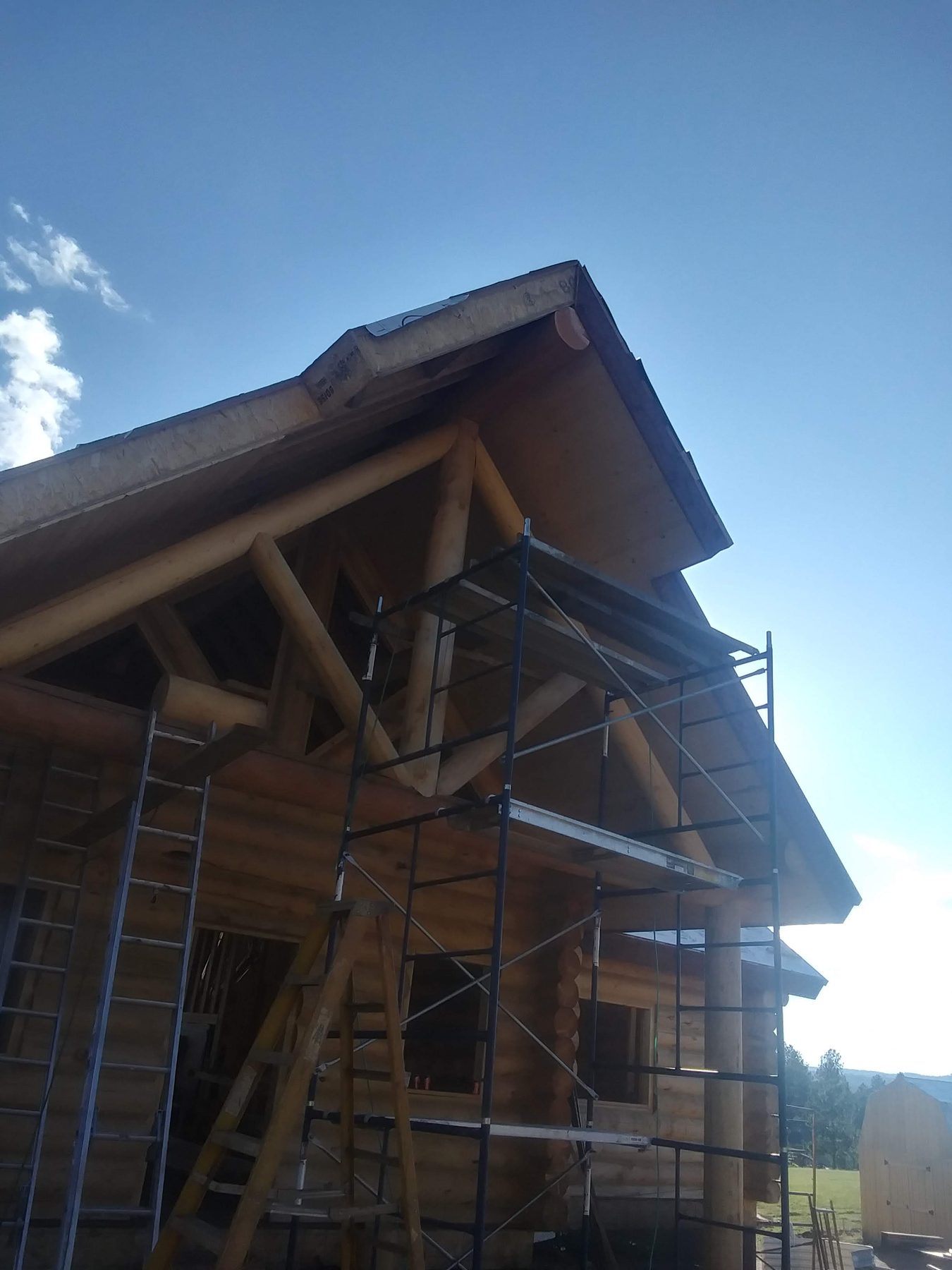 The timber-framed gable against evening sky, roof structure complete.